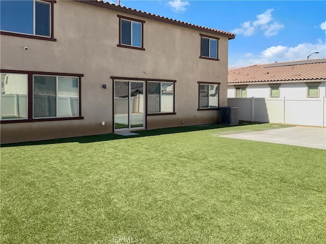 back of property with cooling unit, a yard, and a patio area