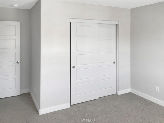 unfurnished bedroom featuring light carpet and a closet