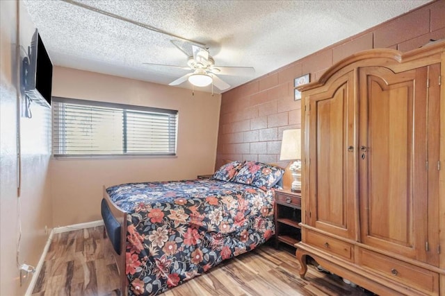 bedroom with ceiling fan, a textured ceiling, and light hardwood / wood-style flooring