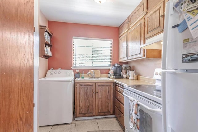 clothes washing area with light tile patterned floors, sink, and washer / dryer