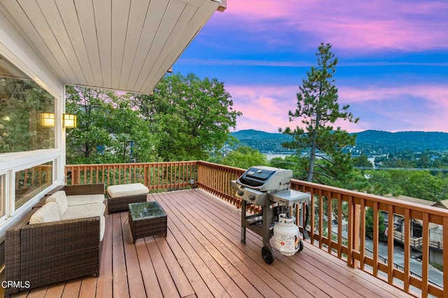 deck at dusk featuring an outdoor living space, a mountain view, and a grill