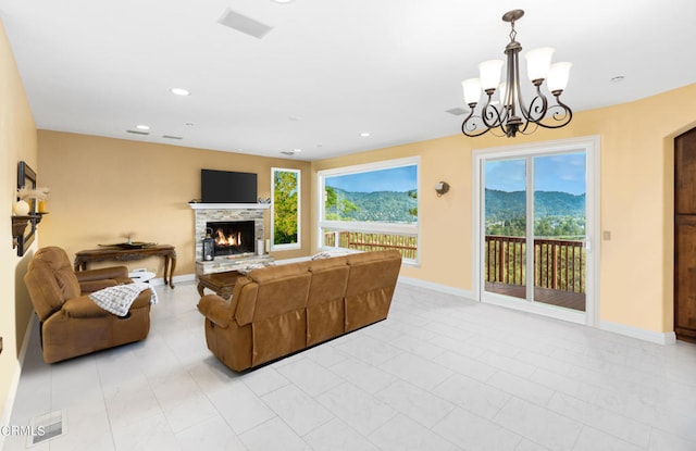 living room with a stone fireplace, light tile patterned flooring, and an inviting chandelier