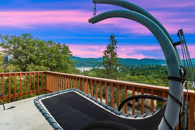 balcony at dusk featuring a water and mountain view