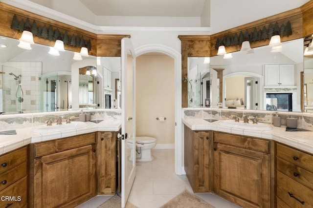 bathroom featuring tile patterned flooring, walk in shower, vanity, and toilet