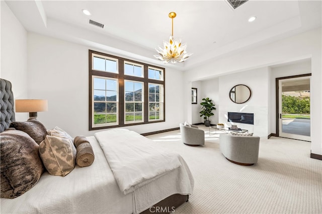 carpeted bedroom with a notable chandelier, a tray ceiling, multiple windows, and access to exterior