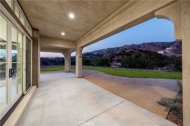 patio terrace at dusk featuring a mountain view and french doors