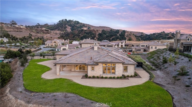 back house at dusk featuring a yard and a mountain view