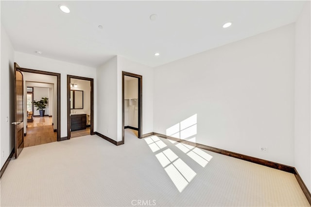 unfurnished bedroom with connected bathroom, a spacious closet, and light colored carpet