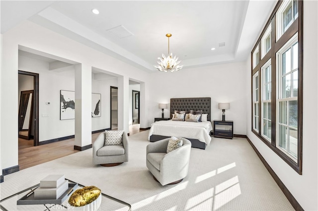 bedroom with a notable chandelier, light wood-type flooring, and a tray ceiling