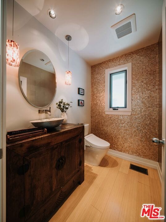 bathroom with wood-type flooring, vanity, and toilet