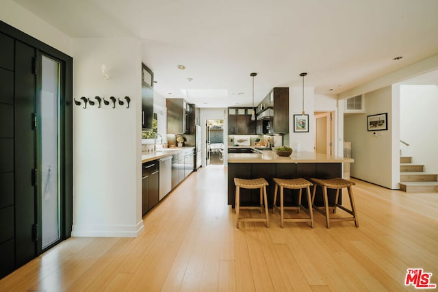 kitchen with light hardwood / wood-style floors, sink, a kitchen island, decorative light fixtures, and stainless steel dishwasher