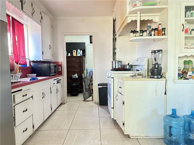 kitchen with sink, crown molding, white cabinetry, white gas range, and light tile patterned floors