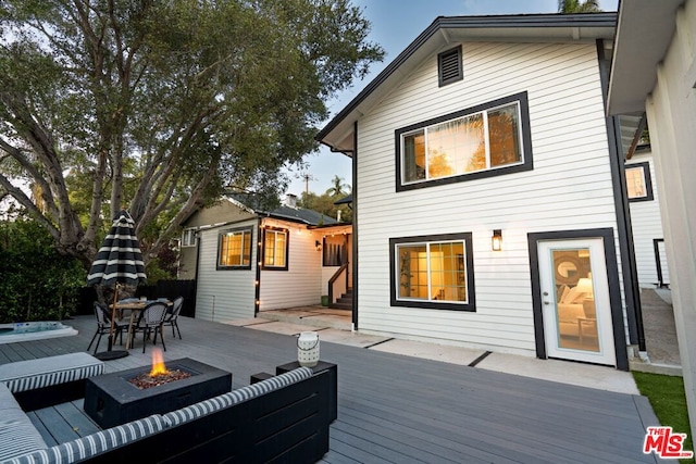 back of house featuring a wooden deck and an outdoor fire pit