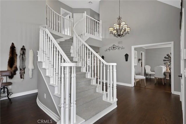 stairway with wood-type flooring, a high ceiling, and a chandelier