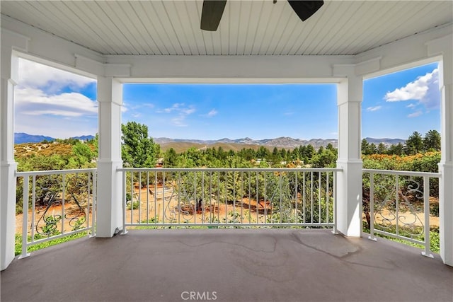 unfurnished sunroom featuring a mountain view and ceiling fan