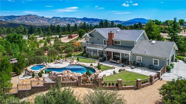 rear view of property with a lawn, a mountain view, a fenced in pool, a balcony, and a patio