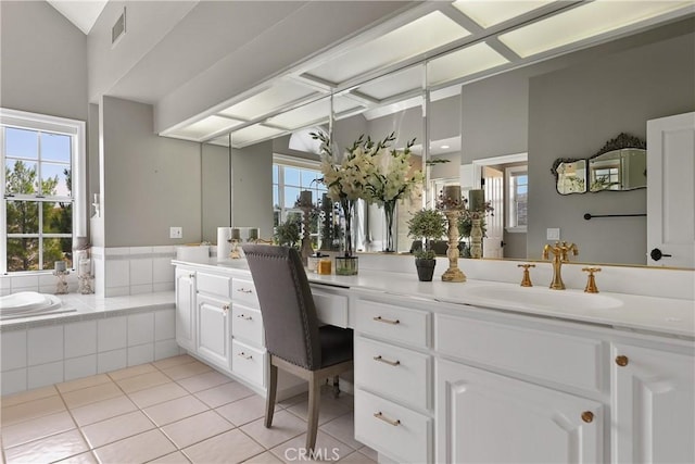 bathroom featuring tiled tub, vanity, and a healthy amount of sunlight