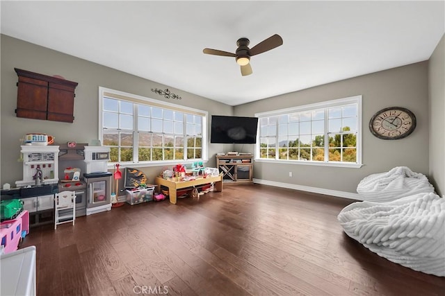 game room with ceiling fan, a healthy amount of sunlight, and dark wood-type flooring