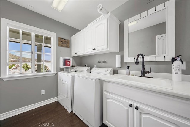 clothes washing area featuring washing machine and clothes dryer, dark hardwood / wood-style flooring, sink, and cabinets