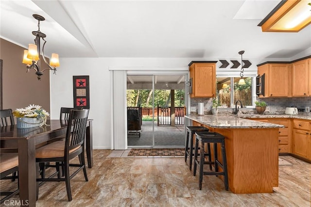 kitchen featuring pendant lighting, backsplash, a wealth of natural light, and a chandelier