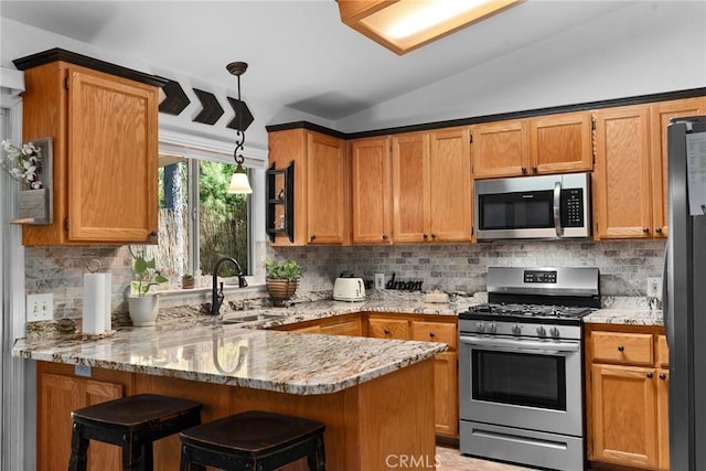 kitchen with kitchen peninsula, appliances with stainless steel finishes, sink, hanging light fixtures, and lofted ceiling