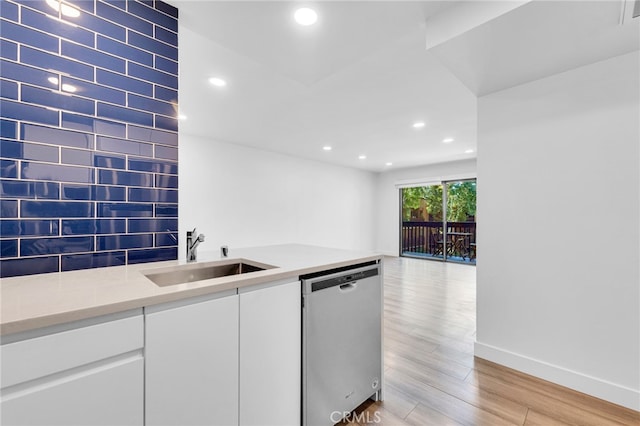 kitchen with white cabinets, sink, stainless steel dishwasher, light hardwood / wood-style flooring, and light stone countertops