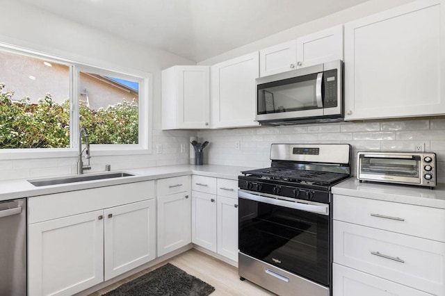 kitchen featuring backsplash, white cabinetry, sink, and appliances with stainless steel finishes