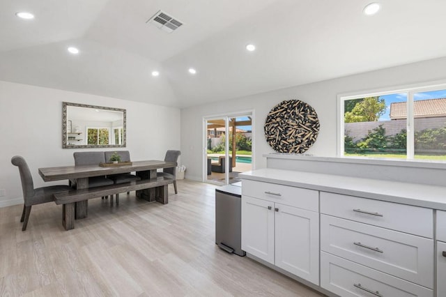 kitchen featuring white cabinets, light hardwood / wood-style floors, lofted ceiling, and a wealth of natural light