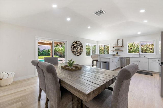 dining space featuring a wealth of natural light, sink, lofted ceiling, and light wood-type flooring