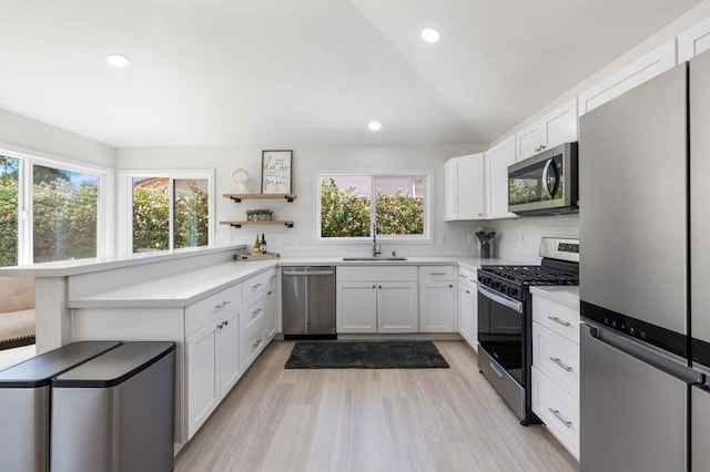 kitchen featuring appliances with stainless steel finishes, white cabinetry, plenty of natural light, and sink