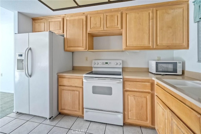 kitchen featuring light brown cabinetry, white appliances, and light tile patterned floors