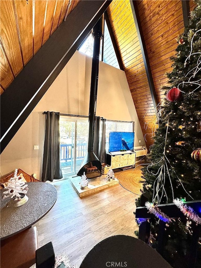 unfurnished living room featuring wood ceiling, a wood stove, hardwood / wood-style floors, and a healthy amount of sunlight