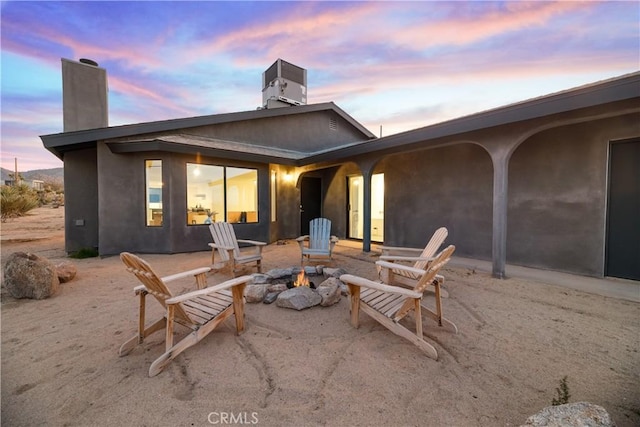 back house at dusk featuring central AC