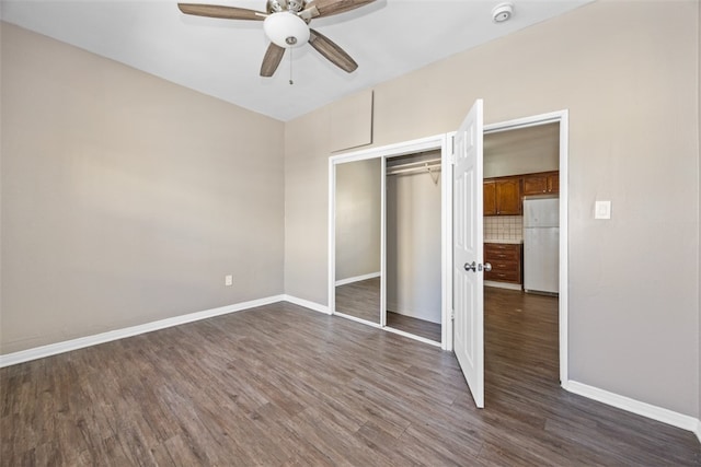 unfurnished bedroom featuring a closet, dark wood-type flooring, ceiling fan, and white fridge