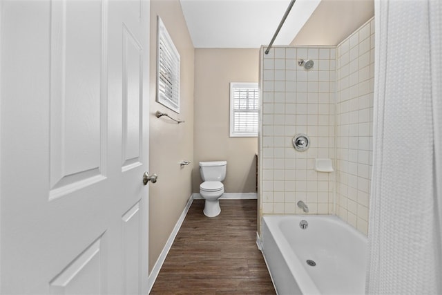 bathroom featuring tiled shower / bath combo, hardwood / wood-style floors, and toilet