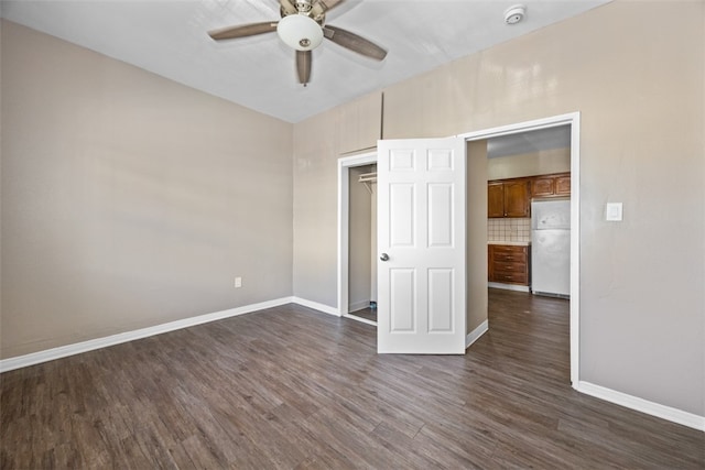 unfurnished bedroom featuring dark wood-type flooring, ceiling fan, and white fridge