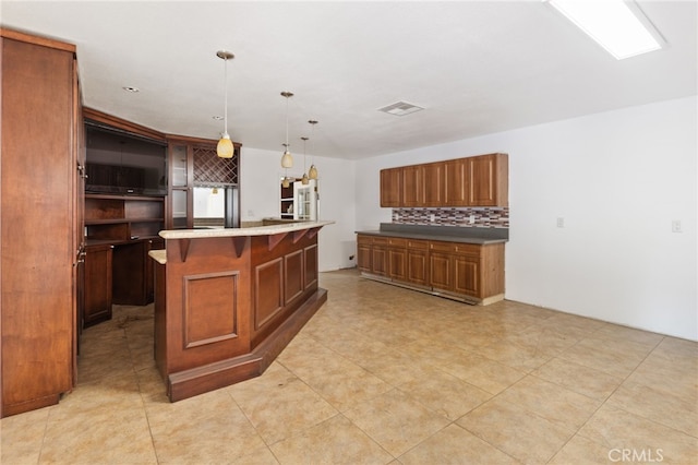 kitchen featuring tasteful backsplash, light tile patterned flooring, an island with sink, and decorative light fixtures