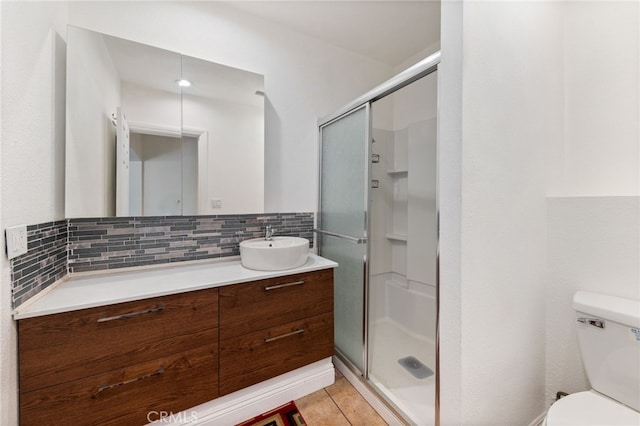 bathroom with vanity, backsplash, toilet, and an enclosed shower