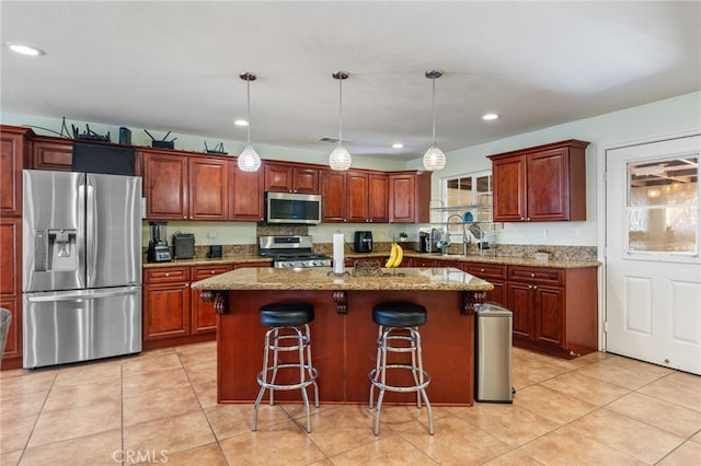 kitchen featuring pendant lighting, stainless steel appliances, light stone counters, and a kitchen island