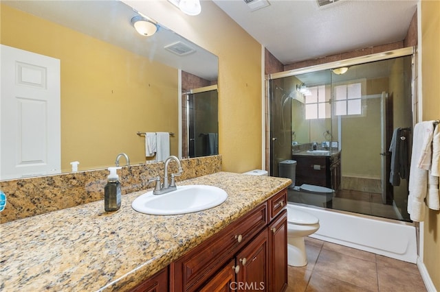 full bathroom with a textured ceiling, tile patterned floors, bath / shower combo with glass door, vanity, and toilet