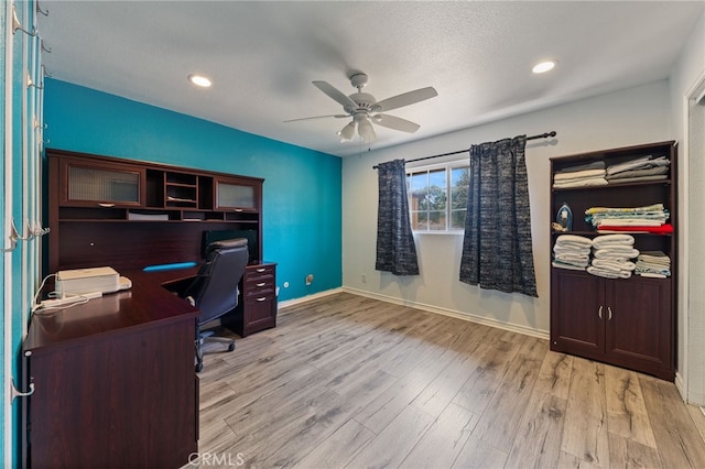 home office with light hardwood / wood-style flooring, ceiling fan, and a textured ceiling