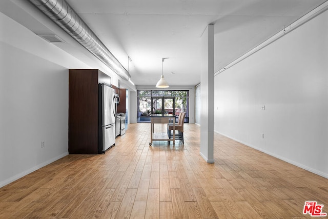 kitchen featuring decorative light fixtures, a kitchen bar, light hardwood / wood-style floors, range, and stainless steel fridge