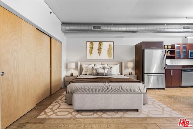 bedroom with a closet, stainless steel refrigerator, and light wood-type flooring