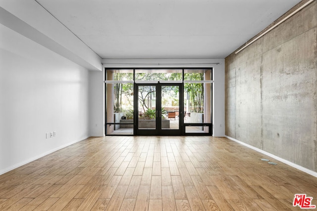 spare room featuring french doors and light wood-type flooring