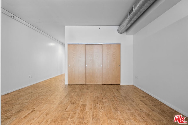 unfurnished bedroom with light wood-type flooring and a closet