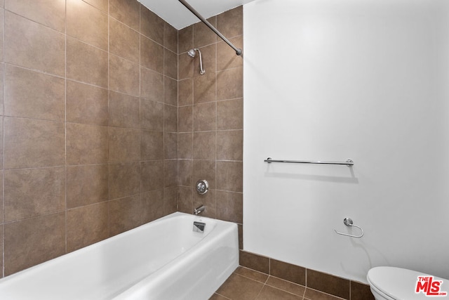 bathroom with toilet, tile patterned floors, and tiled shower / bath