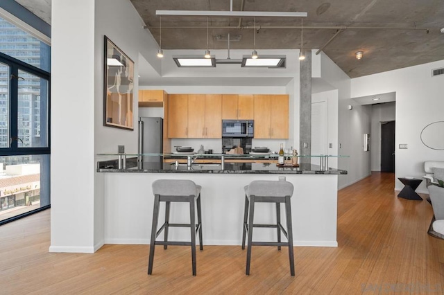 kitchen featuring expansive windows, a breakfast bar, dark stone countertops, and stainless steel appliances