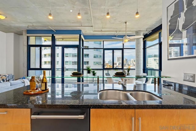 kitchen with hanging light fixtures, sink, and dark stone countertops