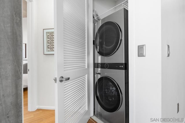 washroom with wood-type flooring and stacked washing maching and dryer