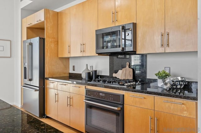 kitchen featuring stainless steel appliances and dark stone countertops